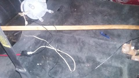 2000 Pontiac Grand Prix - The interior of a vehicle shows a close-up of the floor with various wires and a wooden plank. A blue utility knife is also visible on the…