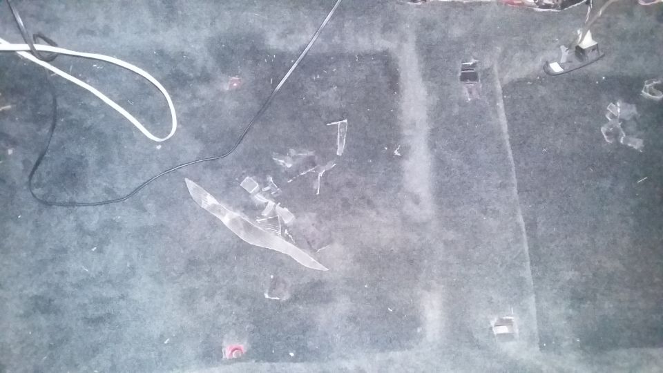 Car interior floor carpet with broken glass shards and electrical wires