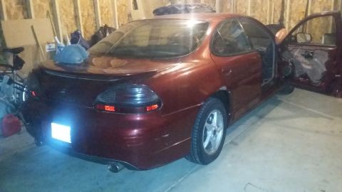 2000 Pontiac Grand Prix - The rear and side of a red sedan are visible in a garage setting.