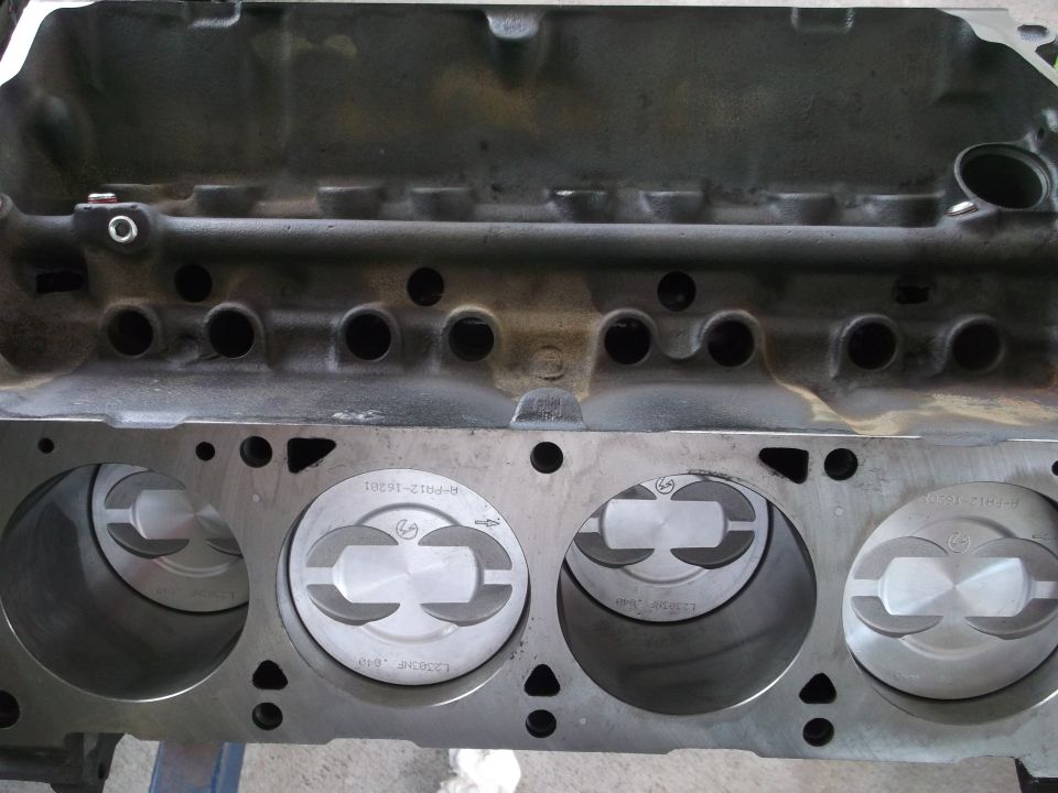 Close-up of engine block showing four cylinders with pistons inside. Some text is visible on the pistons
