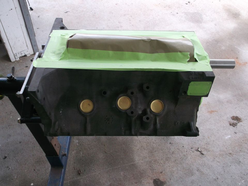 Engine block covered in masking tape and paper, mounted on a stand