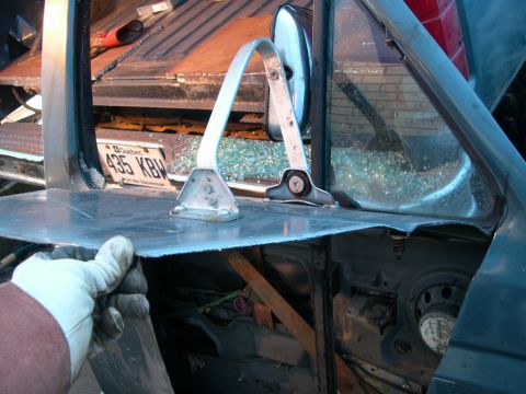 1986 Ford Bronco - A gloved hand inspects damage to the rear window frame and surrounding metal, with shattered glass visible.
