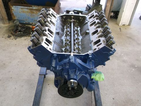 1969 Ford Mustang - A blue V8 engine is mounted on an engine stand, with its internal components visible from above.