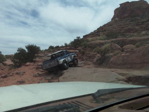 1984 Ford Bronco - Ford pickup truck tackling a challenging off-road course on a cloudy day.