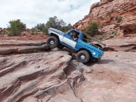 1984 Ford Bronco - This modified 1978 Ford Bronco navigates a rocky trail with a driver inside and "Faded Glory" text on its side.
