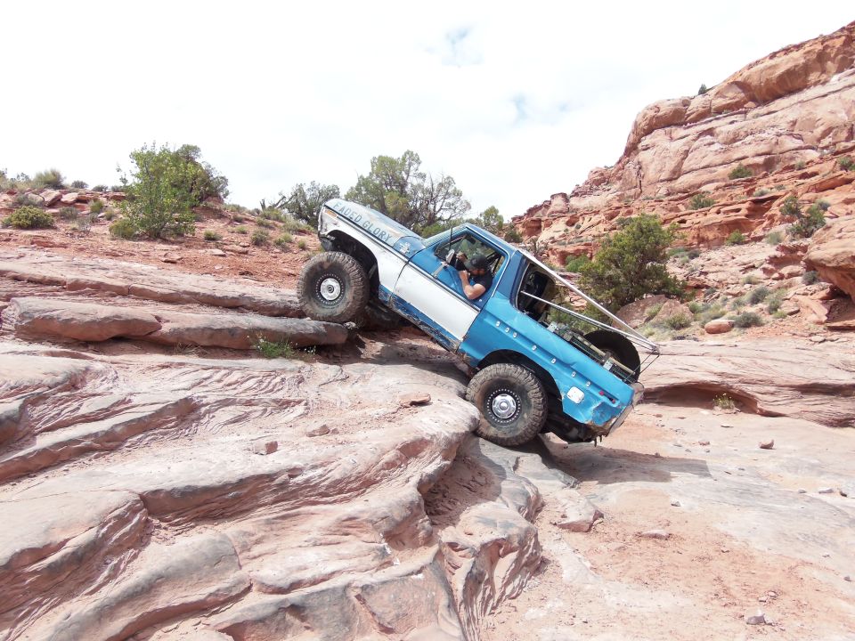 Blue and white off-road vehicle climbing rocks. Text on door reads "SAID GLORY"