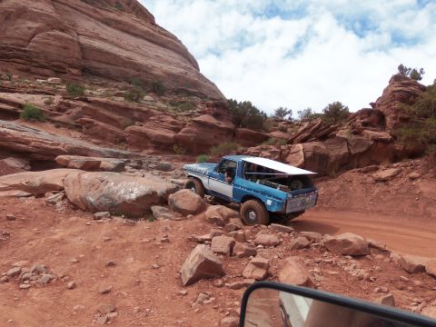 1984 Ford Bronco - Ford Bronco tackles a challenging off-road path through a rocky desert landscape.