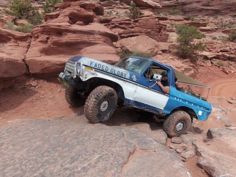 1984 Ford Bronco - Modified Ford Bronco tackling a challenging rocky trail in a desert landscape.