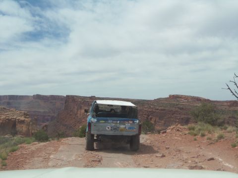 1984 Ford Bronco - A blue Ford Bronco is parked on a dirt road overlooking a canyon.