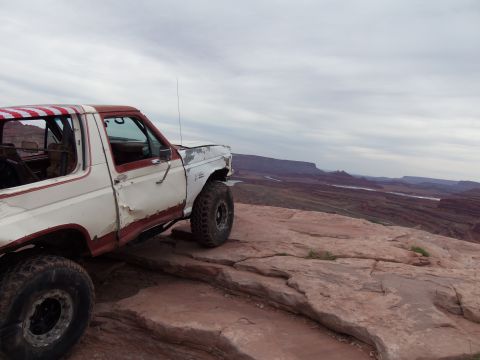 1984 Ford Bronco - Ford Bronco parked on a rocky overlook with a vast canyon landscape in the background.