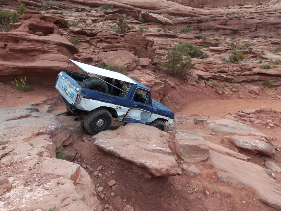 Blue and white 1978 Ford Bronco off-roading on a rocky desert trail