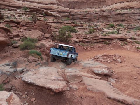 1984 Ford Bronco - Off-road Bronco navigating a challenging rocky trail in a desert canyon.