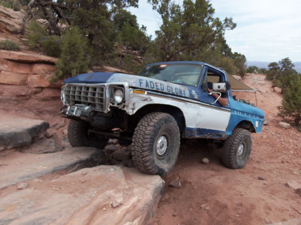 Ford Bronco with "Faded Glory" text on hood, navigating a rock obstacle