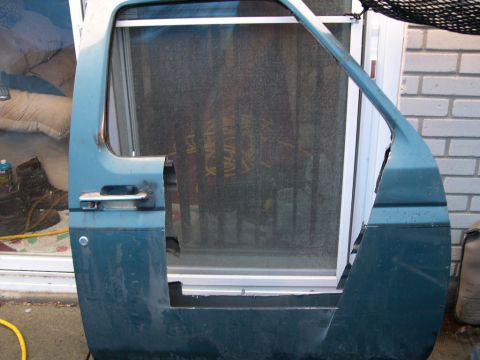 1986 Ford Bronco - A detached teal car door with visible damage and a chrome door handle is shown.