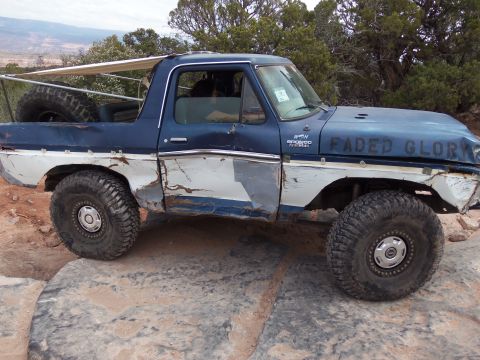 1984 Ford Bronco - This heavily modified Ford Bronco is navigating a rocky trail, its off-road capabilities.