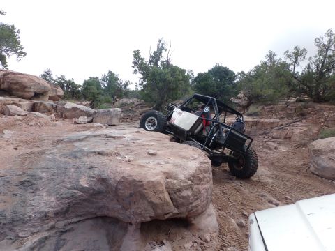 1984 Ford Bronco - An off-road buggy navigates a rocky terrain, with another vehicle partially visible in the foreground.