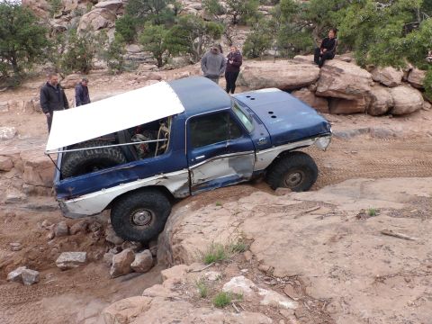 1984 Ford Bronco - This modified Ford Bronco navigates a rocky trail, showing significant wear and tear.