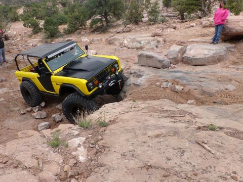 1984 Ford Bronco - A yellow Ford Bronco tackles a challenging rocky off-road course.