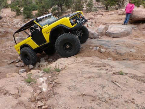 1984 Ford Bronco - A yellow 1984 Ford Bronco navigates a rocky trail, its off-road capabilities.