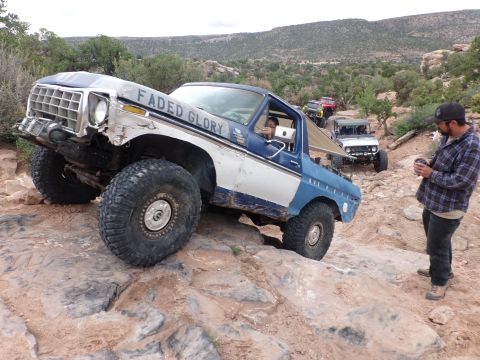 1984 Ford Bronco - This modified Ford Bronco is tackling a challenging off-road course with other vehicles in the convoy.
