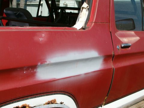 1979 Ford Bronco - Side view of a red vehicle door showing body repair work and rust.
