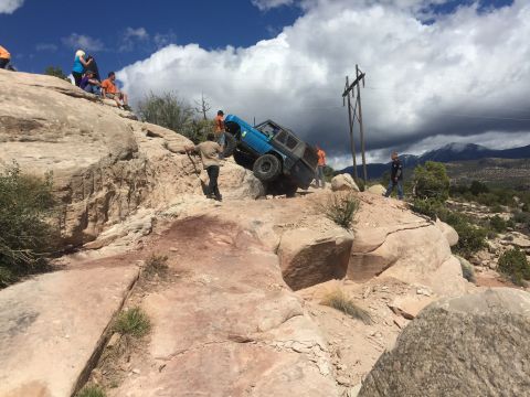 1984 Ford Bronco - Off-road vehicle navigates a challenging rocky trail with spectators observing the action.