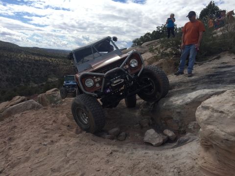 1984 Ford Bronco - An off-road vehicle navigates a rocky trail, with another vehicle visible in the background.