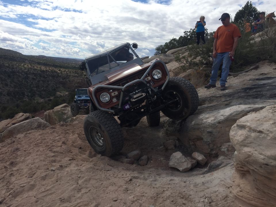Brown off-road vehicle climbing rocks with winch and custom bumper