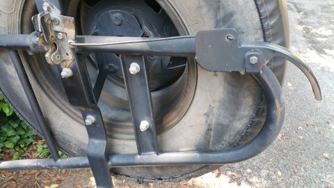 1996 Ford Bronco - Spare tire carrier mechanism shown in detail, attached to a tire.