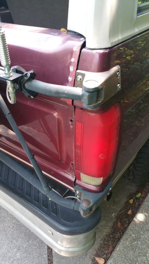 1996 Ford Bronco - Close-up of the rear of a maroon SUV, focusing on the tailgate hinge and bumper assembly.