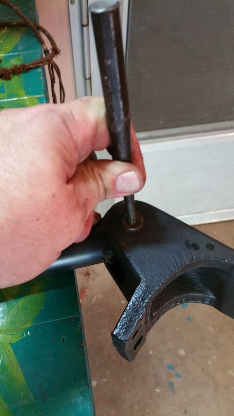 1996 Ford Bronco - Close-up of a hand using a punch tool on a black metal bracket, with SuperMotors.net logo visible.