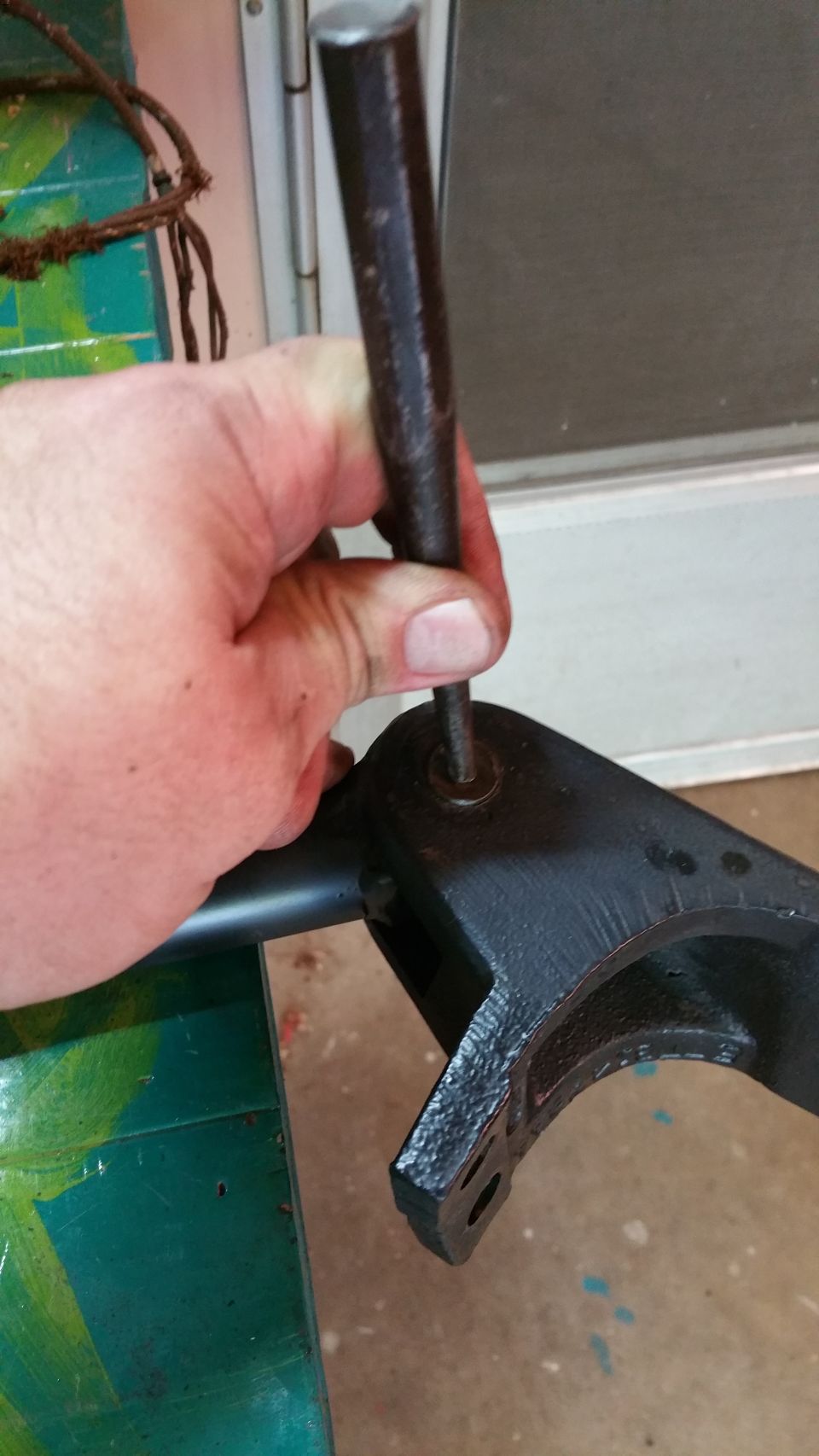 Hand using punch on black metal bracket