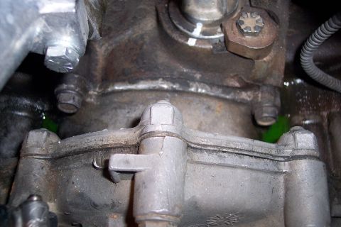 1995 Ford Bronco - Close-up of engine block and transmission housing with green fluid leak.