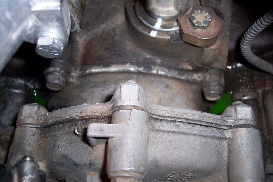 Close-up of engine block and transmission housing with green fluid leak
