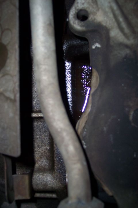 1995 Ford Bronco - Oil is leaking from an engine part, creating a dark puddle with reflective droplets.