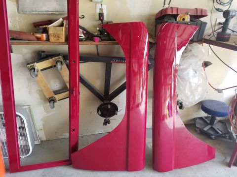 1968 Ford Bronco - Red fenders and door frame parts are stored in a garage with tools and equipment in the background.