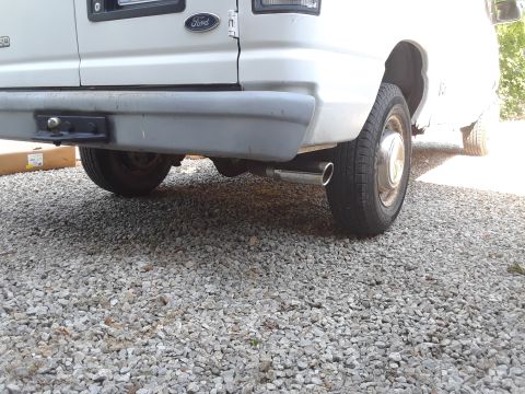 1999 Ford E250 - The rear of a white Ford E-Series van is shown, with a tow hitch and exhaust pipe visible.