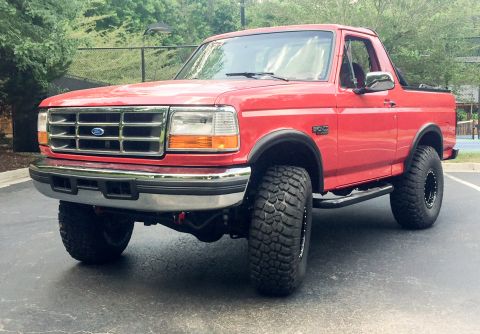 1994 Ford Bronco - This red Ford Bronco is shown from a 3/4 front angle, aftermarket wheels and tires.