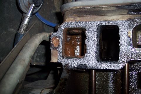 1995 Ford Bronco - Close-up of an engine exhaust manifold gasket showing internal corrosion and buildup.
