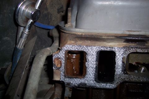 1995 Ford Bronco - Close-up of an engine manifold gasket, showing the ports and a watermark for Supermotors.net.