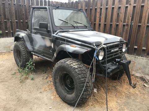 1987 Suzuki Samurai - A modified Suzuki Samurai with a camouflage paint job and heavy-duty off-road tires sits parked outdoors.