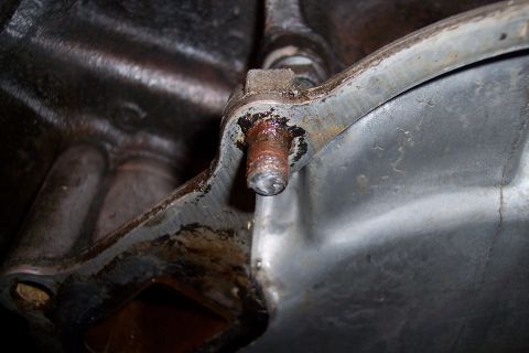 1995 Ford Bronco - A close-up view of a rusty bolt on a metal engine component, with a website watermark visible.