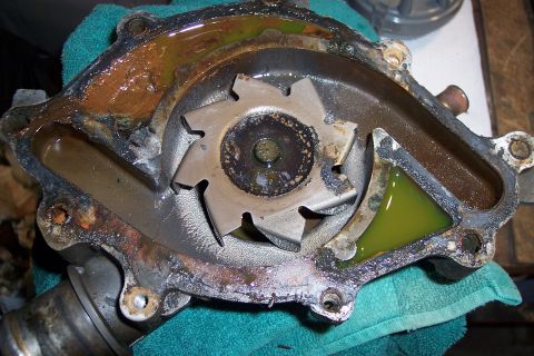 1995 Ford Bronco - A used water pump shows signs of corrosion and contains green coolant, with a Supermotors.net logo in the corner.