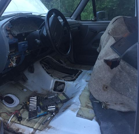 1996 Ford Bronco - The interior of a vehicle is shown with the dashboard, steering wheel, and seats. Tools are laid out on the floor, suggesting ongoing work.