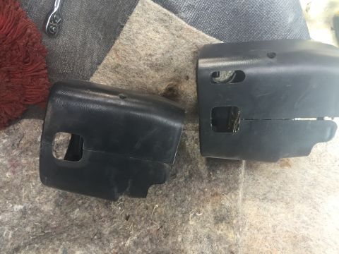 1996 Ford Bronco - Two black plastic steering column covers are shown laid out on a carpeted surface, possibly for a vehicle repair or modification.