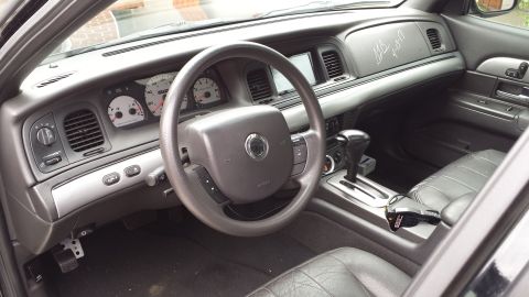 2005 Mercury Grand Marquis - The interior of a car is shown, the steering wheel, instrument cluster, and dashboard with a signature.