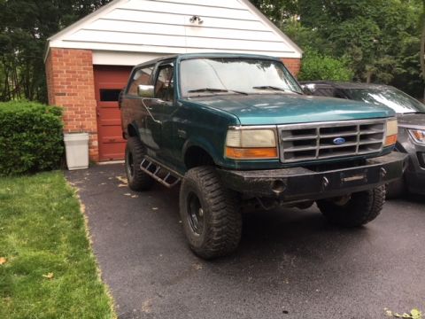 1996 Ford Bronco - This 1996 Ford Bronco is modified with an aftermarket bumper and side steps, parked in front of a garage.