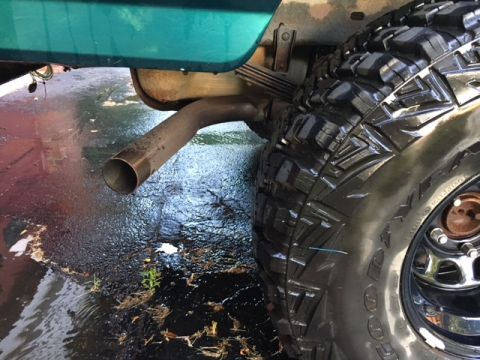 1996 Ford Bronco - A close-up view of a vehicle's exhaust pipe and a tire on a wet surface.