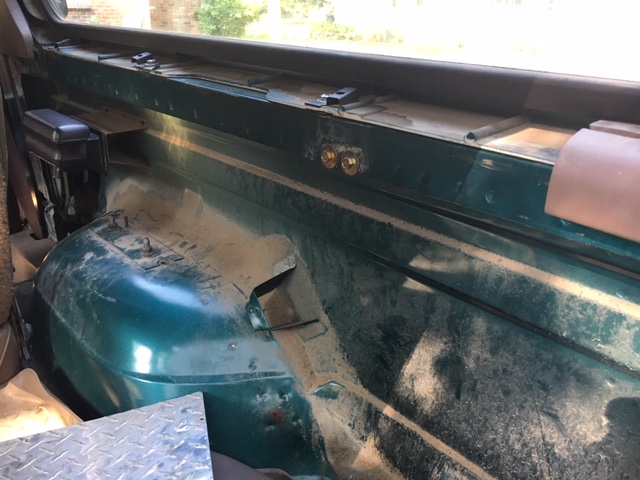 Interior view of a vehicle's cargo area showing the wheel well and some mounting hardware