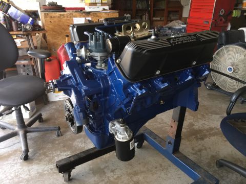 1969 Ford Mustang - A blue 428 Cobra Le Mans engine is mounted on a stand in a garage setting.
